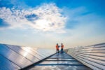Two technicians in distance discussing between long rows of photovoltaic panels. Why should companies care about their carbon emissions?